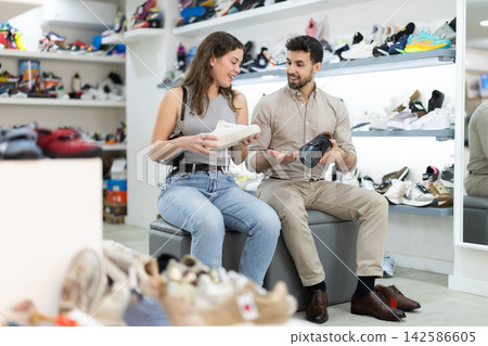 In sales are of store, girl and man sit on couch and puts on shoes 142586605