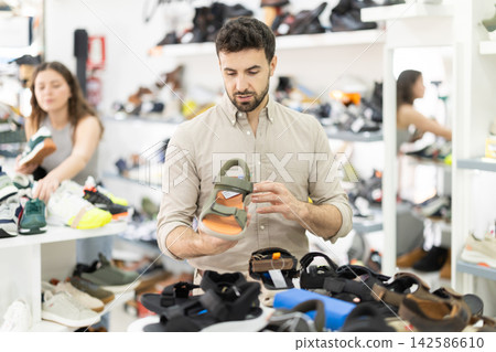 Man spends time in store and pick up sandals Man spends time in store and pick up sandals 142586610