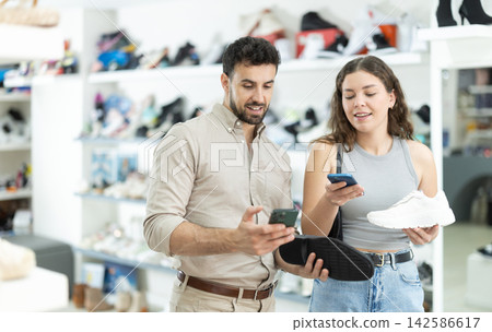 Couple scanning shoe barcode together in store Couple scanning shoe barcode together in store 142586617