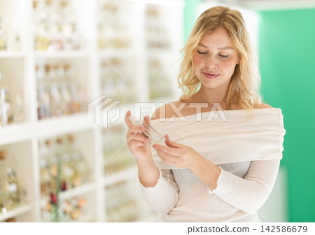 Girl sniffs fragrance of perfume, chooses scent spray Girl sniffs fragrance of perfume, chooses scent spray 142586679