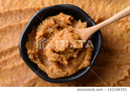 miso paste in a black bowl with wooden spoon 142586781