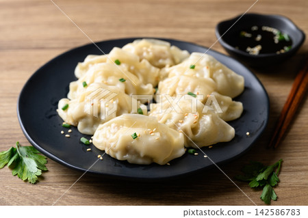 Dumpling stuffed with minced pork on black plate eaten with sesame oil dipping sauce, Asian food 142586783