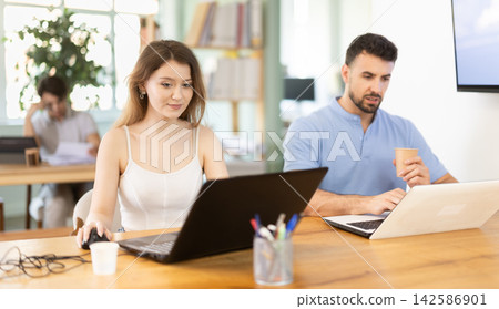 Man and girl staff colleagues working at laptop computer in office room space Man and girl staff colleagues working at laptop computer in office room space 142586901