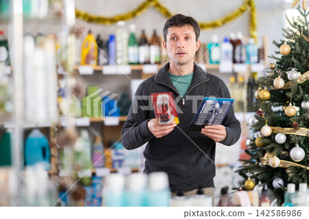 Adult man choosing razor in decorated store Adult man choosing razor in decorated store 142586986