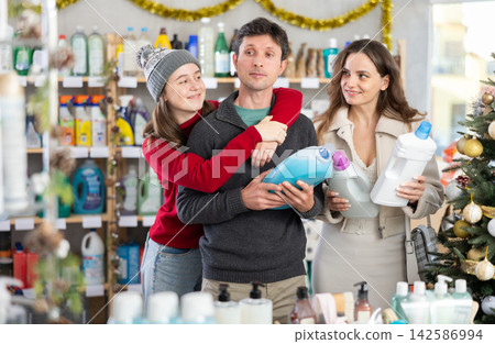 Couple man and woman with daughter choosing detergent in decorated store Couple man and woman with daughter choosing detergent in decorated store 142586994