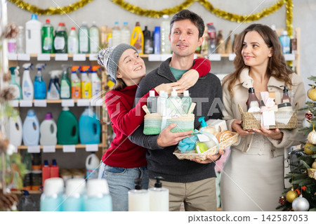 Happy family choosing toiletries gift baskets in Christmas decorated shop Happy family choosing toiletries gift baskets in Christmas decorated shop 142587053