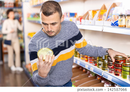 In Russian goods store, man choose canned sprats in oil In Russian goods store, man choose canned sprats in oil 142587066