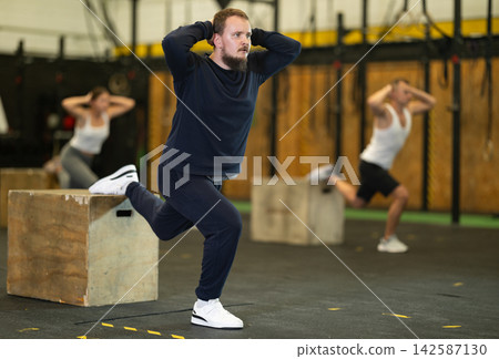 Bearded man performing Bulgarian split squats on box at gym Bearded man performing Bulgarian split squats on box at gym 142587130