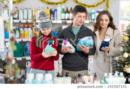 Couple man and woman with daughter choosing detergent and spray in decorated store 142587141