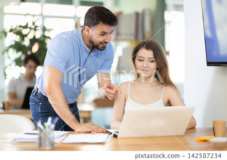Young man helping female colleague with tasks on laptop Young man helping female colleague with tasks on laptop 142587234