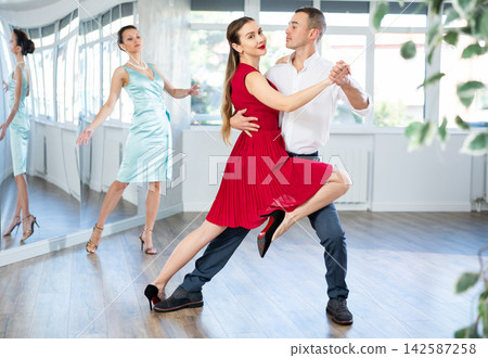 Elegant couple performing expressive tango in dance studio Elegant couple performing expressive tango in dance studio 142587258
