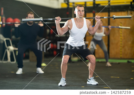 Man performing barbell back squats during cross training at gym Man performing barbell back squats during cross training at gym 142587259