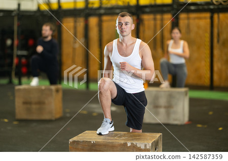 Focused man performing step-ups on box in functional training session Focused man performing step-ups on box in functional training session 142587359