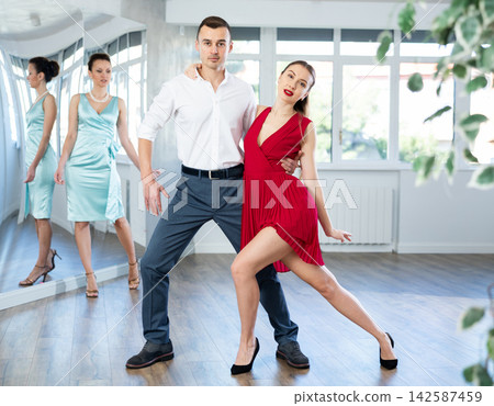 Couple in stage costumes learns tango dancing during individual lesson Couple in stage costumes learns tango dancing during individual lesson 142587459