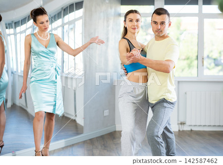Couple in comfortable sports clothes waltz dancing during individual lesson Couple in comfortable sports clothes waltz dancing during individual lesson 142587462