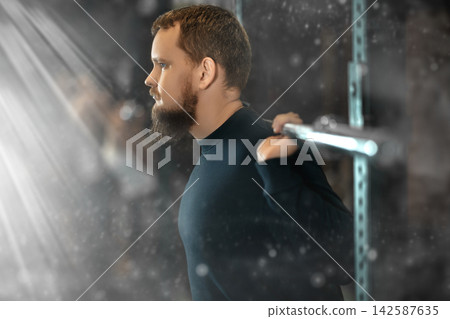 Young bearded man exercising with barbell during intense training Young bearded man exercising with barbell during intense training 142587635