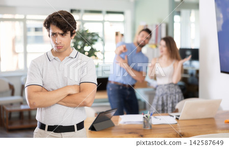 Frustrated man listens obediently to shouts of his office colleagues Frustrated man listens obediently to shouts of his office colleagues 142587649