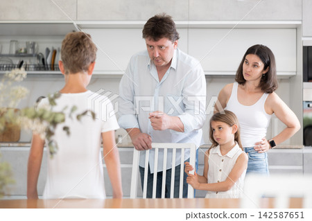 Parents scolding their son in kitchen at home Parents scolding their son in kitchen at home 142587651