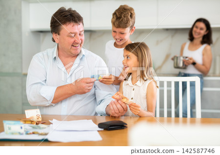 Father gives pocket money to children and wife Father gives pocket money to children and wife 142587746