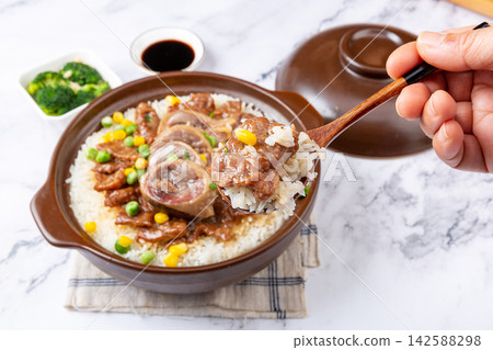 Chinese combo claypot rice with sliced beef and savory cured duck, spoon scooping rice meal Chinese combo claypot rice with sliced beef and savory cured duck, spoon scooping rice meal 142588298