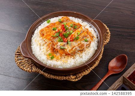 Chinese claypot rice topped with spicy braised ribbonfish fillets on wooden table background Chinese claypot rice topped with spicy braised ribbonfish fillets on wooden table background 142588395
