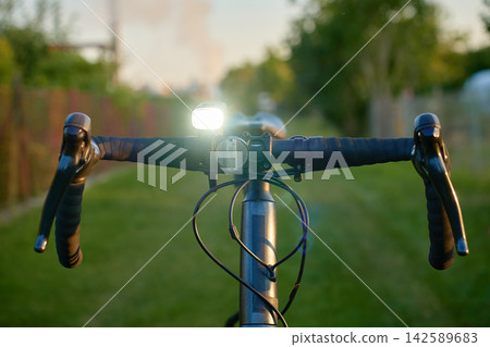 Close-up of a bicycle handlebar with the front light turned on. Close-up of a bicycle handlebar with the front light turned on. 142589683