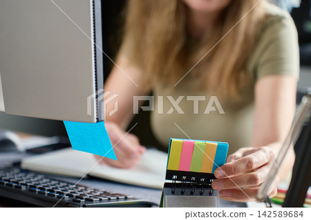 Woman using sticky notes while planning work at home office desk Woman using sticky notes while planning work at home office desk 142589684