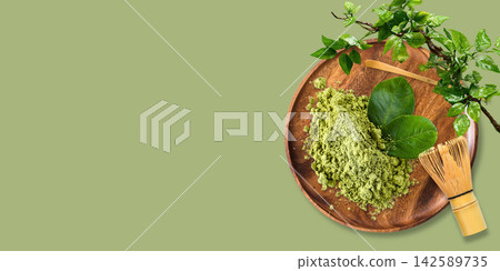 Matcha. Matcha powder and bamboo whisk are arranged on wooden plate Matcha. Matcha powder and bamboo whisk are arranged on wooden plate 142589735