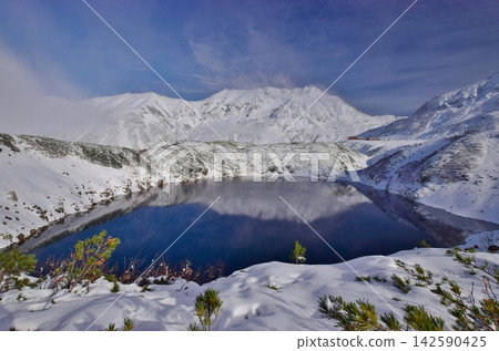 The snow-capped Tateyama mountain range reflected on the water's surface. 142590425
