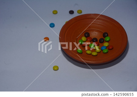Colorful chocolate candies inside an earthen bowl on a neutral table Colorful chocolate candies inside an earthen bowl on a neutral table 142590655