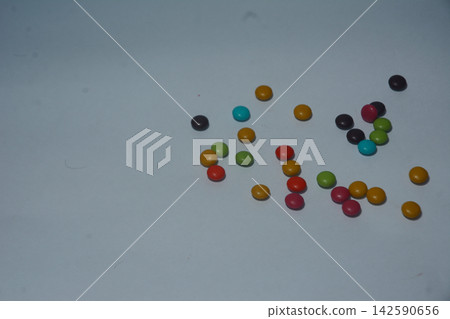 Colorful candy coated chocolate drops scattered on neutral background Colorful candy coated chocolate drops scattered on neutral background 142590656