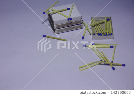 Stack of matchboxes with blue tipped wooden matches on white surface Stack of matchboxes with blue tipped wooden matches on white surface 142590663