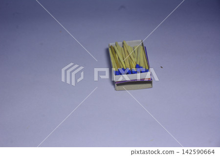 Open matchbox with blue tipped wooden matches on a plain surface Open matchbox with blue tipped wooden matches on a plain surface 142590664