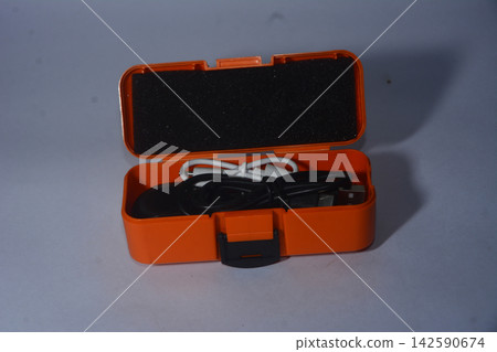 Bright orange plastic storage box containing electronic cables and wire Bright orange plastic storage box containing electronic cables and wire 142590674