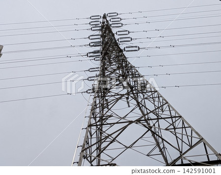 一座輸電塔高聳於陰雲密佈的天空下,電線向外輻射。 一座輸電塔高聳於陰雲密佈的天空下,電線向外輻射。 142591001
