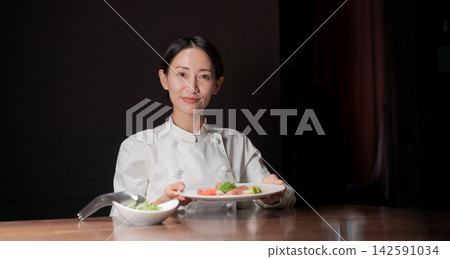一位微笑的女廚師正在烹飪(橫幅) 一位微笑的女廚師正在烹飪(橫幅) 142591034