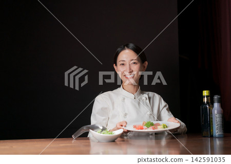 一位微笑的女廚師正在烹飪。 一位微笑的女廚師正在烹飪。 142591035