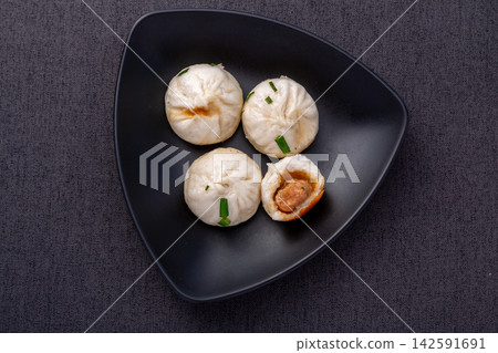 pan fried pork buns with green onions on black plate, Chinese shengjian baozi dumplings pan fried pork buns with green onions on black plate, Chinese shengjian baozi dumplings 142591691