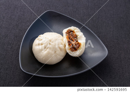 steamed pork and preserved mustard greens buns on black plate, traditional Chinese meigancai baozi steamed pork and preserved mustard greens buns on black plate, traditional Chinese meigancai baozi 142591695