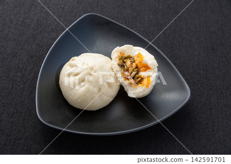 steamed pork and pickled cowpea sour beans buns on black plate, authentic Chinese savory baozi 142591701