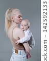 Young Mother Holding Her Baby Boy in a Calm Embrace 142592133