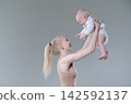 Young Mother Lifting Her Laughing Baby Boy in the Air 142592137