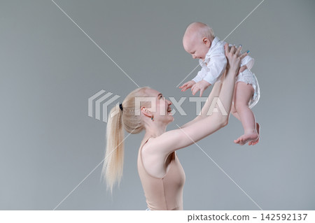 Young Mother Lifting Her Laughing Baby Boy in the Air Young Mother Lifting Her Laughing Baby Boy in the Air 142592137