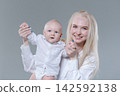 Young Mother Holding Her Baby Boy Hands, First Steps 142592138