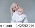 Young Mother Cuddling Her Baby Boy Cheek to Cheek 142592149