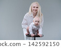 Baby Boy on a Wooden Stool with His Smiling Mother 142592150