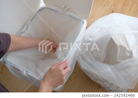 Replacing the trash bag in the bathroom trash can. Replacing the trash bag in the bathroom trash can. 142592460