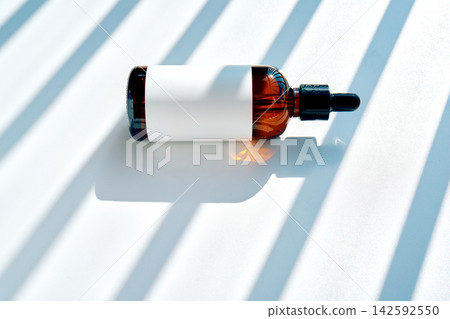 Serum dropper bottle lying on white background with shadows Serum dropper bottle lying on white background with shadows 142592550