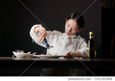 一位表情嚴肅的女廚師正在做飯。 142592900