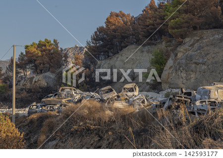 Burned out cars scattered across a rocky hillside under evening light Burned out cars scattered across a rocky hillside under evening light 142593177